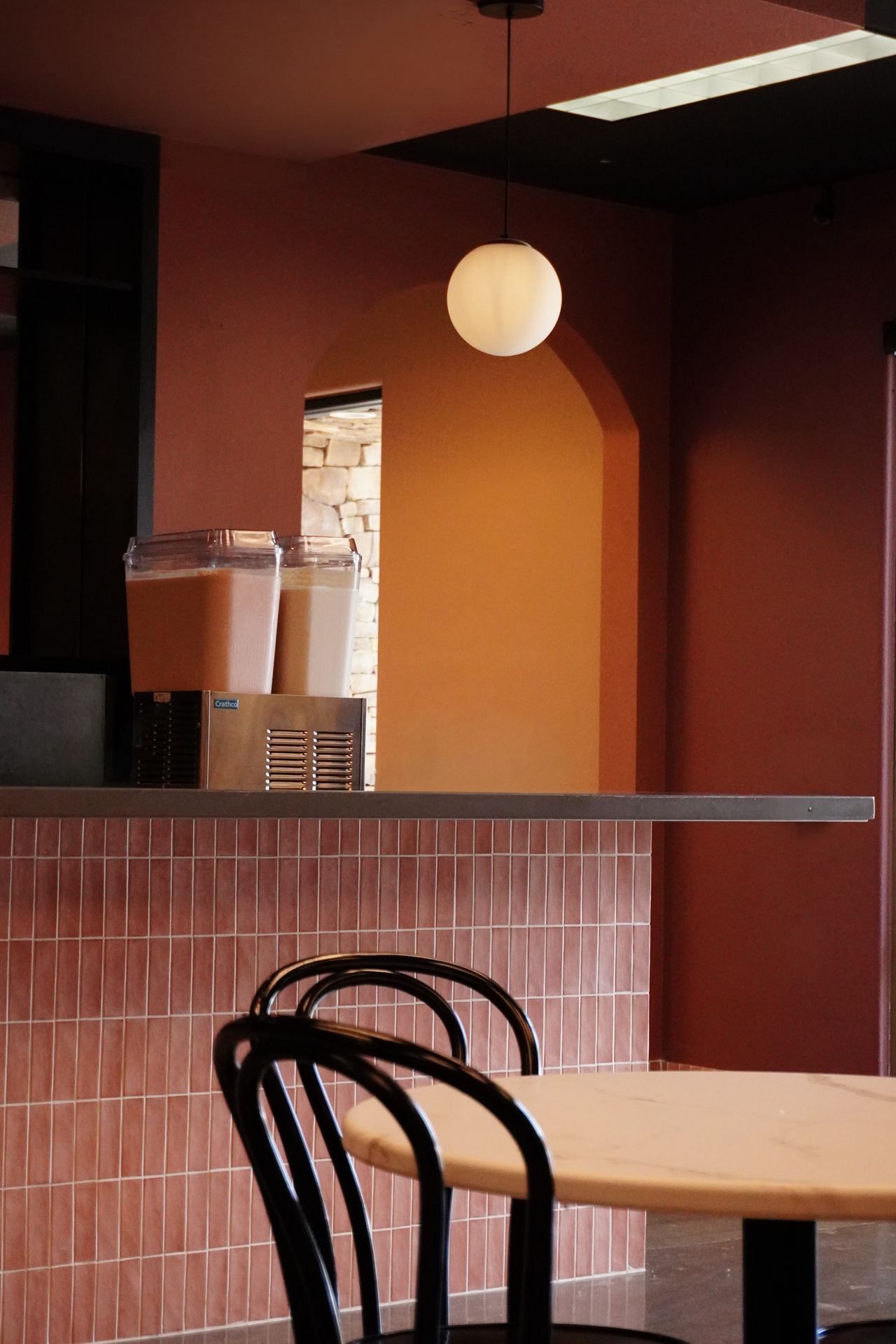 Inside Casa de Silvia — terracotta walls, a pendant globe light, and the counter with horchata dispensers